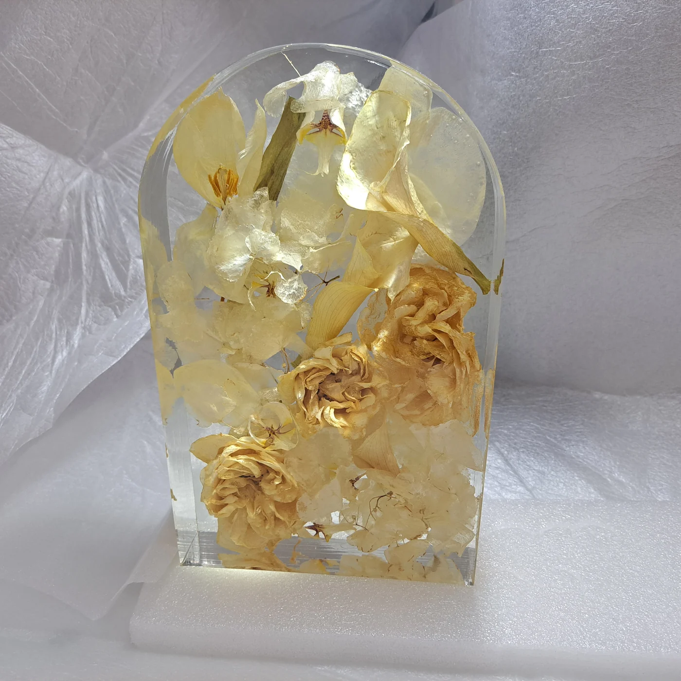 Ivory roses and orchids preserved in an arch-topped resin block